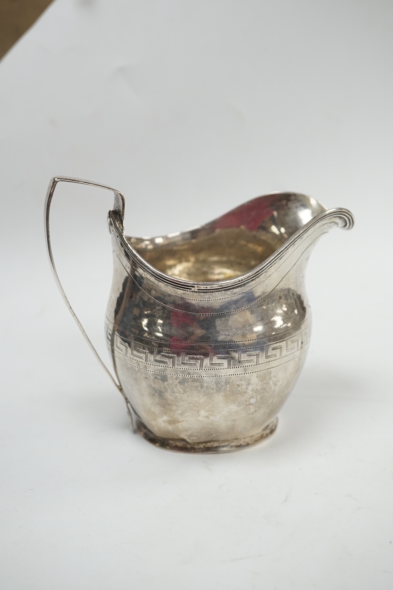 A quantity of assorted small silver including a George III cream jug(a.f.), three small capstan inkwells, a watch stand, photograph frame, mounted glass toilet jars etc. Condition - poor to fair